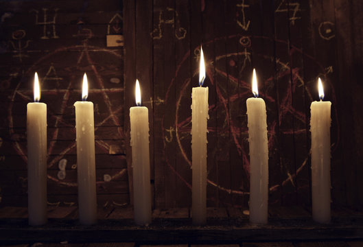 Mystic close up wih burning candles against wooden background with magic symbols