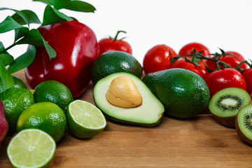 A selection of juicy fruits and vegetables on a wooden and white background.