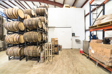 Stack of barrels in cellar with stainless steel brewing equipments in a modern microbrewery in...