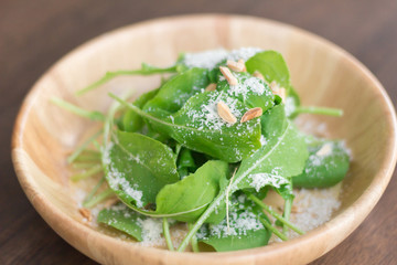 Fresh salad with mixed greens (arugula, mesclun, mache) on light wooden background close up. Healthy food.