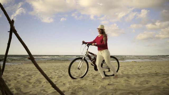 Young long hair woman enjoying windy summer day on sandy beach dunes  Active girl with bicycle on seaside. Female tourist resting near to sea  on fresh air 4K ProR es HQ codec