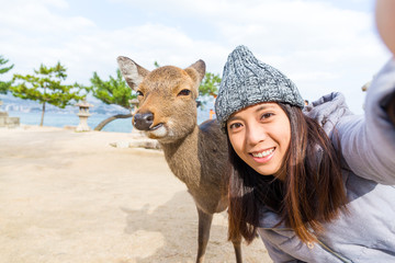 Woman takign selfie with deer in Itsukushima
