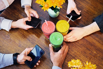 People's arms, smartphones and  vegetarian juice.