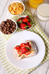 Obraz na płótnie Canvas breakfast: Fresh toast with strawberry, banana and nuts, cornflakes, orange juice, milk