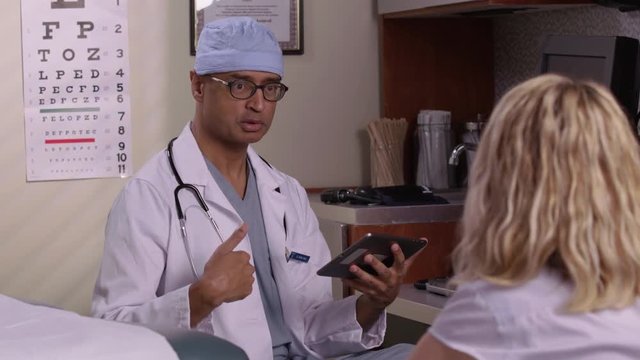 Doctor with digital tablet meeting and talking with patient