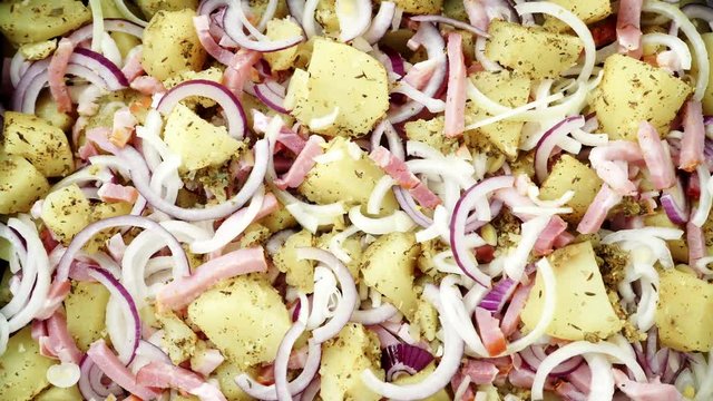 Peeled potatoes with spices, becon meat and onion slices ready to be roasted close up. Food background. Rack focus 4K ProRes HQ codec