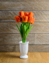 orange tulip flowers bouquet in vase on wooden floor