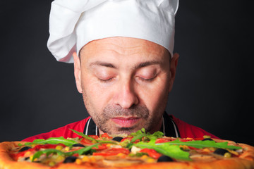 Portrait of happy attractive cook with a pizza