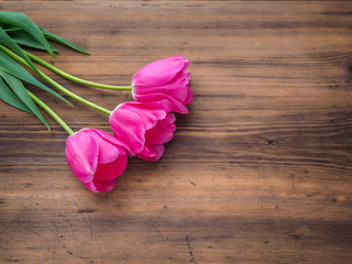 Pink tulips, floral arrangement on wooden background from old boards and a space for messages. Background for Mother's Day, 8 March and other greeting cards for lovely women. Soft focus, top view.