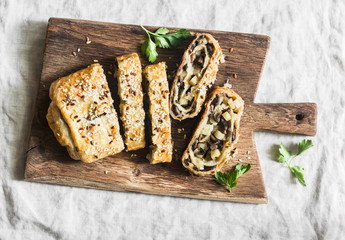 Mushroom and potato strudel on a rustic wooden cutting board, top view
