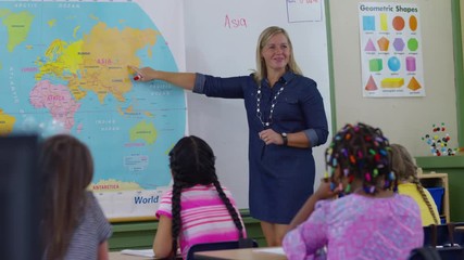 Teacher gives lesson in school classroom and students raise hands