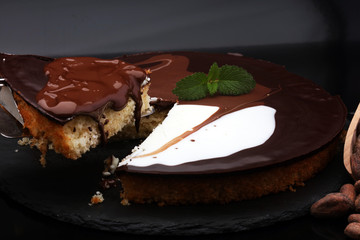 Delicious chocolate cake on dark background with cocoa beans