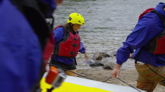 Group of people white water rafting carry raft together