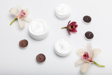 Fototapeta na wymiar Close-up view of organic cream in containers with orchids and candles isolated on white