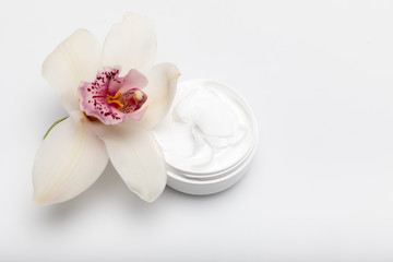 Close-up view of organic cream in container with orchid isolated on white