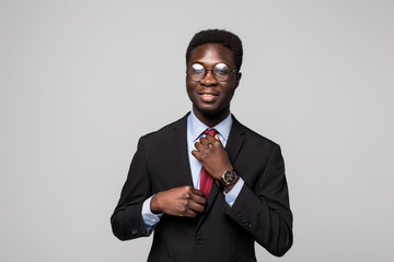 Handsome black business man make his tie on suit on grey background