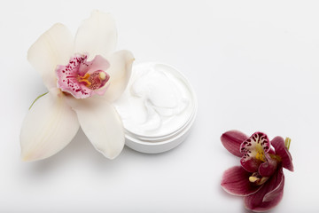 Close-up view of organic cream in container with orchids isolated on white