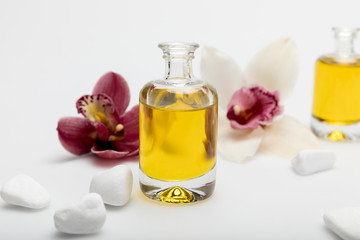 Close-up view of essential oil, white stones and orchids isolated on white