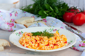 Scrambled eggs with tomatoes and cheese on a plate with white bread, horizontal