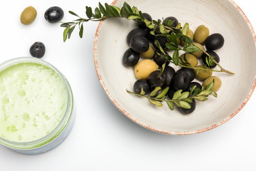 Top view of organic cream in container and olives isolated on white