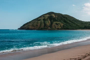 Foto op Canvas Landscape with a tropical beach with green hills, rocks on the background, water is azure and sand is white, Indonesia, Lombok © ArinaEmelyanova
