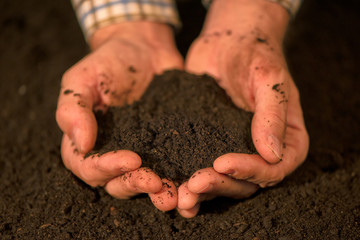 Handful of arable soil in hands of responsible farmer