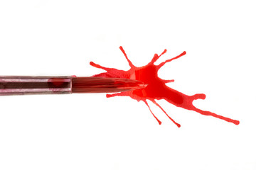 close up view of brush in red paint and splash on white