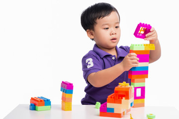 Kid boy playing with blocks from toy constructor isolated