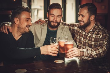 Cheerful old friends having fun and drinking draft beer in pub.