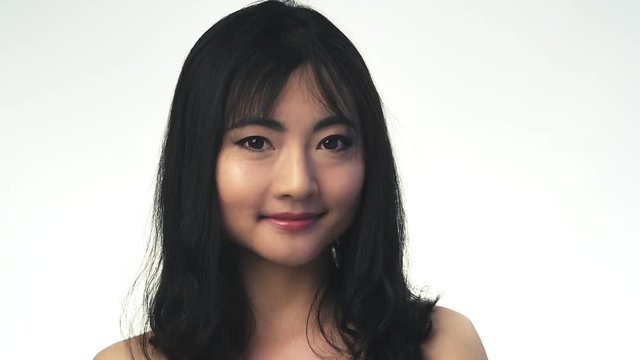 Pretty smiling asian girl posing over white background.