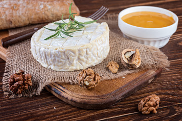 Fototapeta na wymiar Camembert cheese with walnuts and honey on wooden rustic background