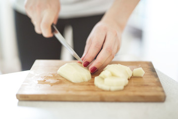 Cutting potatoes on close-up in real interior