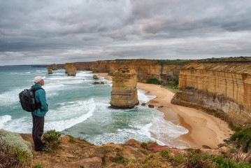 Fototapeta premium Young hiker stands above the Twelve Apostles along the famous Great Ocean Road in Australia