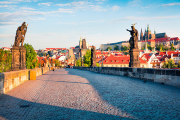 Naklejka premium Sunny spring scene on Charles bridge on Vltava river (Karluv Most) with statues and Prague castle