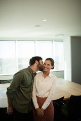 Fototapeta na wymiar Businessman kissing businesswoman in meeting room