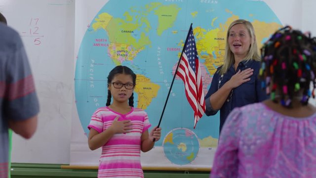 Teacher and student saying pledge of allegiance in school classroom