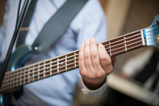 Male hand holding guitar fret. Playing the music background.