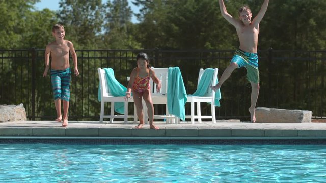 Three kids jumping into pool in super slow motion