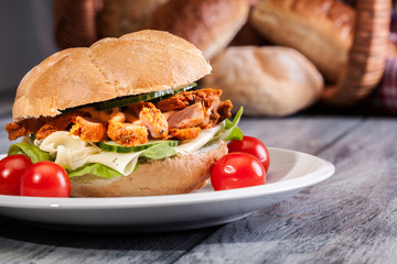 Fried chicken meat with cheese and vegetables in bun