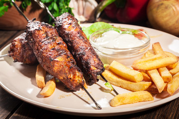 Grilled shish kebab served with fried chips and salad