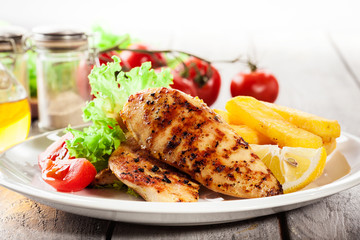 Grilled chicken breasts served with fries and fresh salad