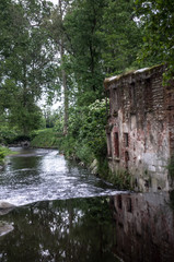 Scene from another era, an old mill in the park with the river placid flowing 