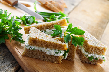 Sandwiches made of rye bread, cream cheese, green onion and fresh parsley on a rustic table. Delicious healthy appetizers. Close-up shot.