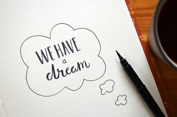 WE HAVE A DREAM written in notepad on desk with cup of coffee 