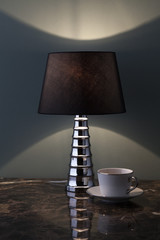 elegante lampada da tavolo accesa su piano in marmo, vicina a tazza da tè.