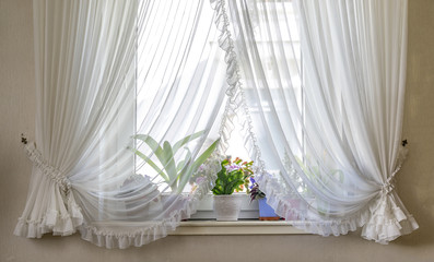 Old fashioned grandparents window sill with curtains and flower heads