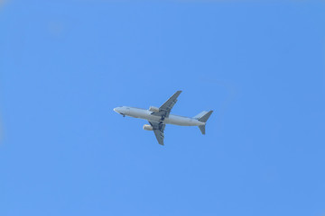 White passenger plane flies highly in the sky on a bright Sunny day without clouds