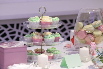 Sweet cupcakes and macarons are on table during celebration