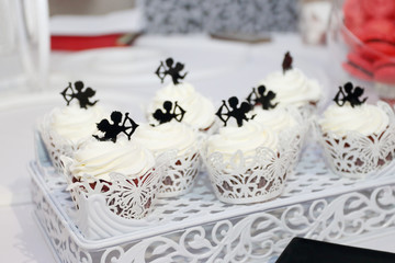 Obraz na płótnie Canvas Sweet white cupcakes with small cupids are on table during celebration