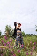 fashion outdoor portrait of a beautiful brunette woman with flowers in hair in the field